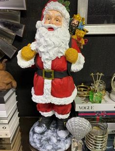 a santa clause figurine sitting on top of a table next to stacks of books