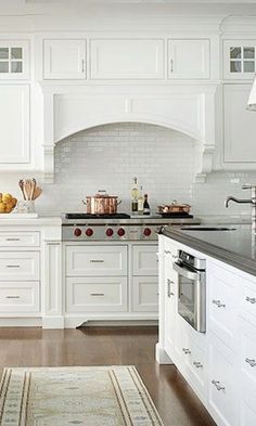 a large kitchen with white cabinets and black counter tops, an area rug on the floor