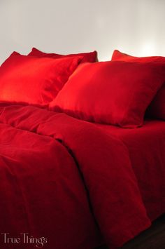 a bed with red sheets and pillows on it