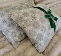 two pillows with green bows on them sitting on a bed