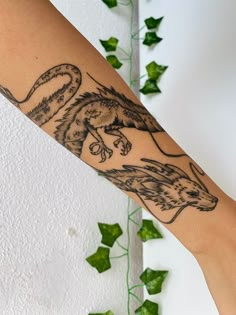 a woman's arm with a tiger tattoo on it and green ivys in the background