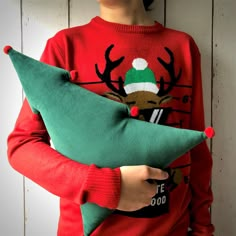 a young boy holding a green and red christmas pillow