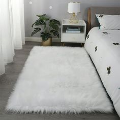 a white rug is on the floor next to a bed and nightstand with a lamp