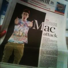 a person holding up a newspaper with the word mac attack on it's front page