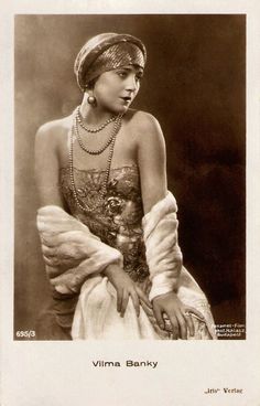 an old fashion photo of a woman wearing pearls and necklaces, sitting down with her hands on her hips