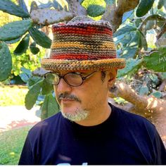 a man with glasses and a hat is standing in front of a cactus tree looking at his cell phone