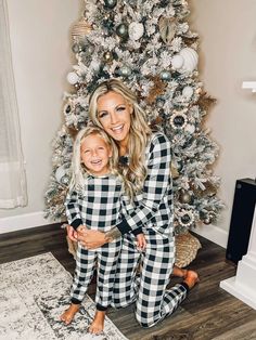 a woman and her child are posing in front of a christmas tree