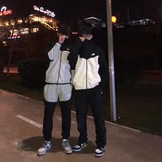 two young men standing next to each other in front of a street sign at night