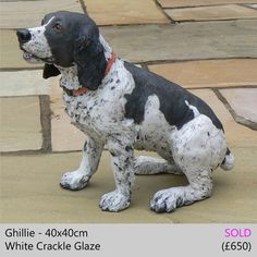 a black and white dog figurine sitting on top of a tile floor next to a brick walkway