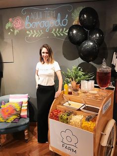 a woman standing in front of a bar cart filled with fruit and vegetables, surrounded by balloons