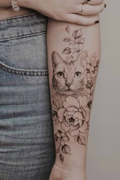 a woman's arm with a cat and flowers on it