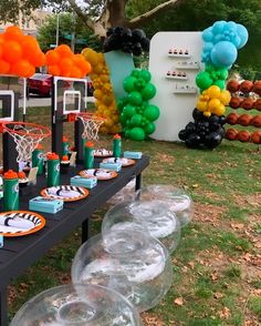 the table is set up with balloons and basketballs on it for an outdoor party