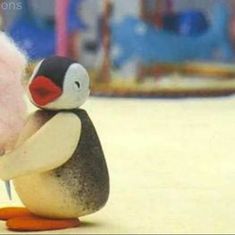 a small toy penguin holding a pink wool ball and knitting needles in it's beak