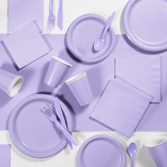 the table is set with purple plates, napkins, and silverware on it