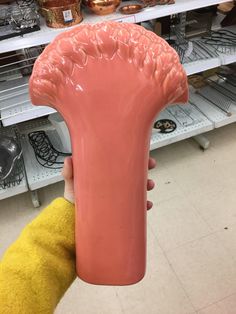 a person holding up a large pink object in a room filled with shelves and other items