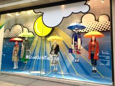 a window display with mannequins holding umbrellas