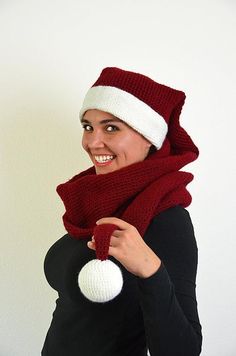 a woman wearing a knitted hat and scarf holding a white ball in her hands