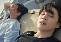 two young men laying on the back of a boat next to each other, one with his eyes closed