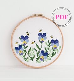 a cross stitch pattern with blue and yellow flowers in the center, on a white background