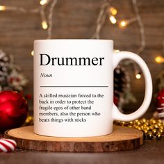 a white coffee mug sitting on top of a wooden table next to christmas decorations and ornaments