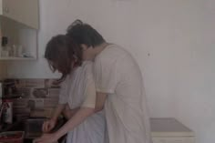 two people standing in a kitchen preparing food