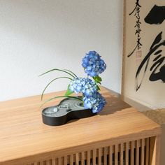 This is an ikebana flower vase made of aluminum, crafted using the traditional technique of Takaoka copperware. Uniquely shaped akin to a gourd, the upper side is in a silver-gray color and adorned with harmonious ripple-shaped decorations, evoking the ambiance of a Japanese garden. The sides finished in a textured matte black achieve a striking contrast. This vase includes a kenzan, a metallic flower frog to set flowers and greenery. Even those new to ikebana will be able to create artistic floral arrangements by fixing blooms onto the needles of the small-sized kenzan. Each piece is handmade using the sand casting technique where metallic bases are made by pouring hot metal into hardened sand molds. This traditional technique has been handed down in Takaoka City for over 400 years. The p Flower Vase Making, Ikebana Flower, Daruma Doll, Decorative Stand, Japanese Tea Cups, Japanese Teapot, Sake Set, Sushi Plate, Bamboo Basket