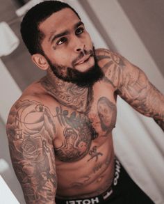 a man with tattoos on his arms and chest standing in front of a bathroom mirror