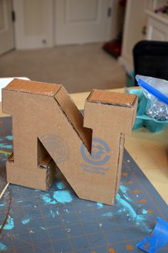 the letter n is made out of cardboard and sits on a table next to paint