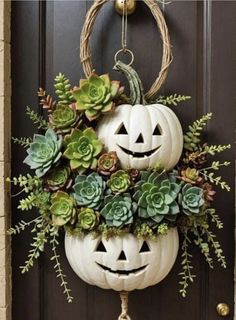 two pumpkins decorated with succulents and greenery are hanging on the front door