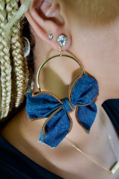 a close up of a person wearing ear rings with a blue bow on the side