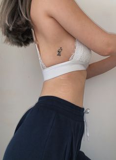 a woman with her back to the camera wearing a white bra and blue sweatpants