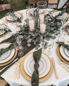 the table is set with place settings, candles and greenery for an elegant dinner