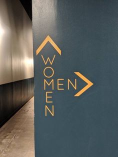 a sign that says women on it next to a wall with an arrow in the middle