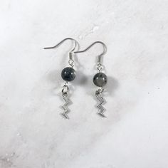 These Zeus earrings are the perfect accessory to show your love for the Greek gods in a subtle way! Made with labradorite gemstone and a lightning bolt charm. Made with hypoallergenic fishhook style earrings. Two options are available: Stainless Steel Silver Plated Brass Ships in a jewelry box so it's ready to be give as a gift. All materials are lead and nickel free. Charm is made with zinc alloy. Earrings will be disinfected before shipment but should also be cleaned every time before wearing. Zeus Jewelry, God Greek Mythology, The Greek Gods, Greek Mythology Jewelry, Mythology Jewelry, Greek God, Alloy Earrings, Greek Gods, Lightning Bolt