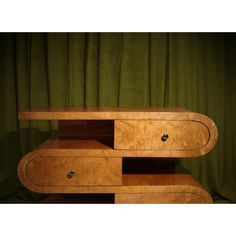 a wooden table with two drawers on one side and green curtains in the back ground