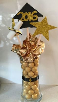 a glass vase filled with chocolate covered candies and graduation cap on top of it