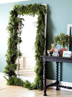 a mirror sitting on top of a wooden table next to a wall covered in greenery