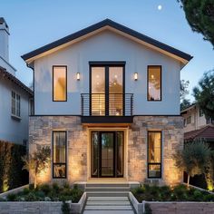 a modern house is lit up at night with lights on the front and side windows