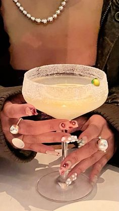 a woman holding up a martini glass with her hands and nails on the rims