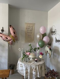 a table topped with lots of balloons next to a wall filled with flowers and other decorations