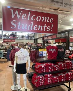 there is a sign that says welcome students in front of some shirts and t - shirts