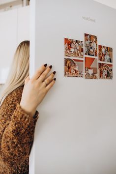 a woman is looking at pictures on the wall in front of her and touching it with her hand