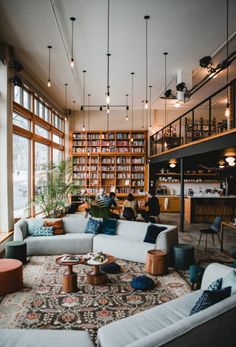 a living room filled with lots of furniture next to a tall book shelf full of books