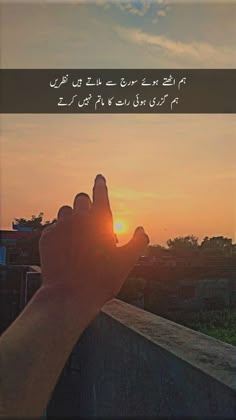 someone is holding their hand up to the sun in front of them with arabic writing