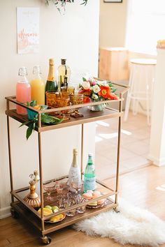 a bar cart filled with drinks on top of a hard wood floor next to a white rug