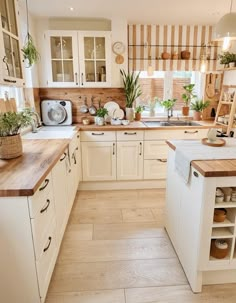 a kitchen filled with lots of white cabinets and wooden counter top space next to a window