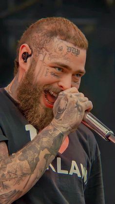 a bearded man with tattoos holding a microphone