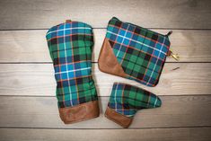 two green and blue plaid boots sitting on top of a wooden floor next to a wallet