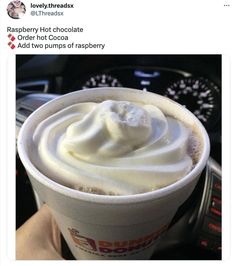 a cup with whipped cream in it sitting on top of a car steering wheel next to a dashboard