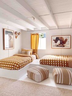 two beds in a room with white walls and yellow curtains on the windowsills